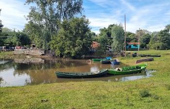 Vista del río Tebicuary con embarcaciones amarradas, rodeado de vegetación y casas de colores en Villa Florida.