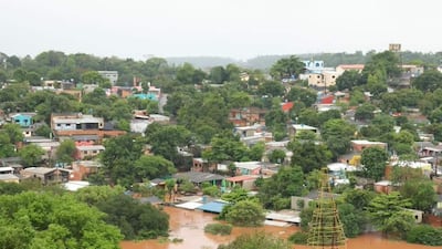 Paisaje urbano inundado en Ciudad del Este, con edificios y casas anegados por el agua, reflejando un ambiente de emergencia.