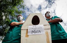 Médicos protestan con ataúdes simbólicos con el mensaje "La corrupción mata", durante unas protestas para denunciar la falta de medicamentos y recursos para combatir el covid-19, hoy, frente al Hospital de Clínicas en San Lorenzo (Paraguay).