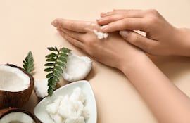 Mujer se aplica aceite de coco en las manos.