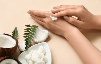 Mujer se aplica aceite de coco en las manos.