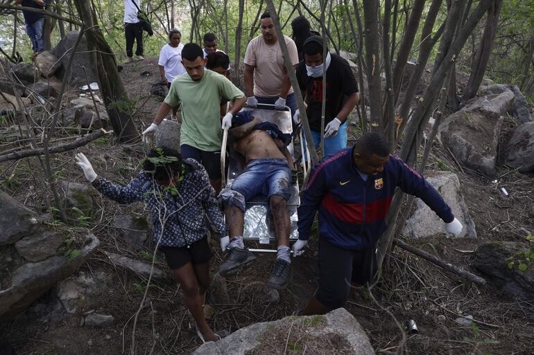 Personas retiran un cuerpo sin vida de una zona boscosa este miércoles, en la favela Vila Cruzeiro en Río de Janeiro (Brasil).