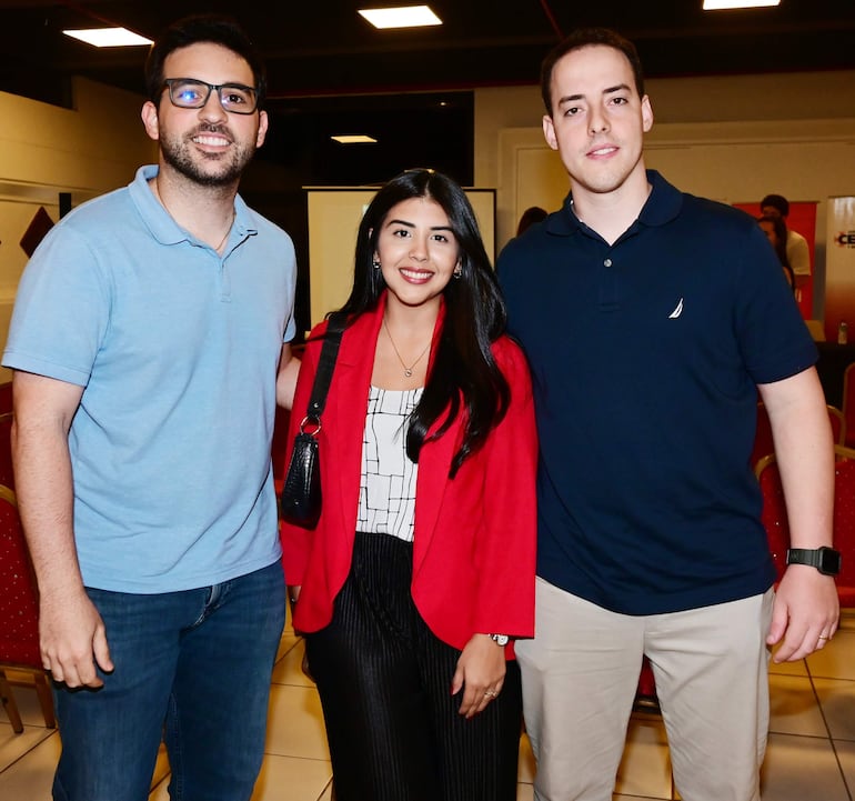 La imagen muestra a tres mujeres posando juntas en un entorno interior bien iluminado. La primera mujer, a la izquierda, tiene el cabello largo y oscuro, lleva una blusa negra y un blazer rosa junto con jeans. La mujer del centro tiene el cabello corto y oscuro, viste un vestido con un patrón floral en colores verdes y azules, complementado por un blazer negro. La tercera mujer, a la derecha, tiene cabello largo y lleva una blusa negra con un blazer rosa. 

Todas están sonriendo y parecen estar en un ambiente social o de evento, posiblemente una reunión o celebración. No se observan elementos que identifiquen a un equipo de fútbol, ni lugares, monumentos o estadios reconocibles. No hay texto visible ni objetos relevantes de contexto noticioso en la imagen.