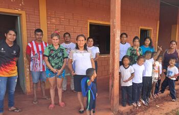 Niños y familias de la escuela indígena Río Verde, de Curuguaty, posan junto a los horcones de madera carcomidos por insectos.