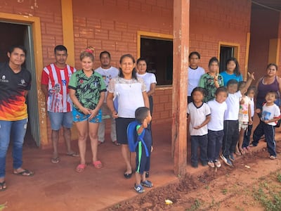 Niños y familias de la escuela indígena Río Verde, de Curuguaty, posan junto a los horcones de madera carcomidos por insectos.