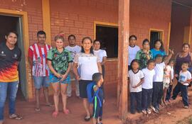 Niños y familias de la escuela indígena Río Verde, de Curuguaty, posan junto a los horcones de madera carcomidos por insectos.