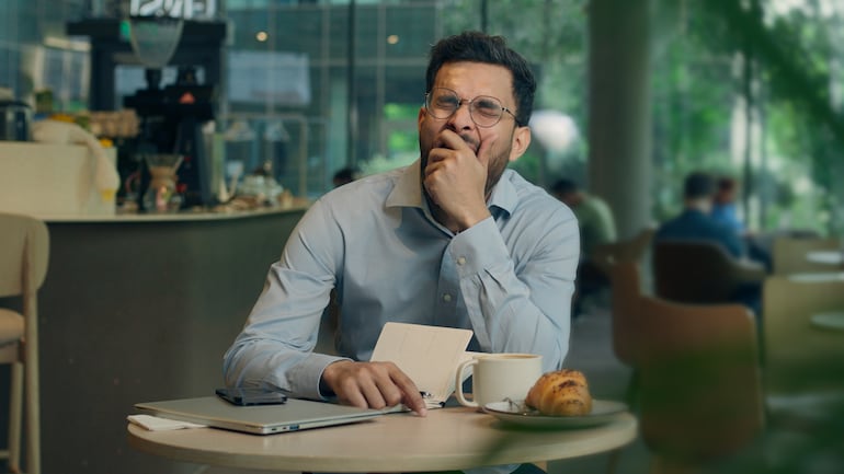 Hombre bosteza sentado en una cafetería.