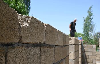 Trabajadores construyen una casa con bloques de arroz, elaborados principalmente con cáscara de arroz —un subproducto del procesamiento del cereal— en la aldea de Kyzyl-Kiya, en el sur de Kirguistán, el 22 de mayo de 2025.