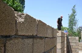 Trabajadores construyen una casa con bloques de arroz, elaborados principalmente con cáscara de arroz —un subproducto del procesamiento del cereal— en la aldea de Kyzyl-Kiya, en el sur de Kirguistán, el 22 de mayo de 2025.