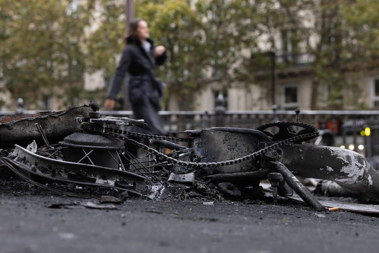Una mujer pasa junto a los restos de una bicicleta calcinada en el centro de París.