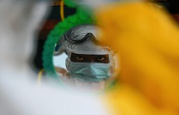 Un trabajador de Médicos Sin Fronteras con traje de protección se mira en un espejo en Kailahun, Guinea, en agosto de 2014.
