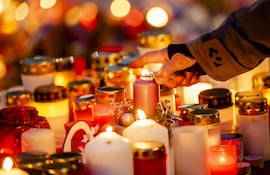 Una persona enciende velas en homenaje a los fallecidos en el incendio en Crans-Montana, Suiza.