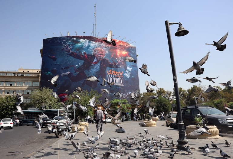 Aves revolotean cerca de una valla publicitaria que muestra al presidente de EE. UU., Donald Trump, en Teherán, 24 de agosto de 2026.