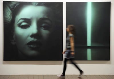 Fotografía de archivo fechada el 24 de marzo de 2011 que muestra a una mujer junto a un retrato de Marilyn Monroe del artista ruso Alexander Timofeev durante la exposición 'El mito Marilyn' en la galería Leerer Beutel en Regensburg (Alemania). Monroe fue mucho más que el icono de glamour que la convirtió en mito global.