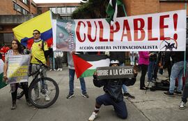 Detractores del expresidente de Colombia Álvaro Uribe, sostienen carteles afuera del Complejo Judicial de Paloquemao este lunes, en Bogotá (Colombia).