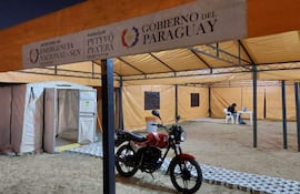Carpas naranjas de la SEN en el exterior, una persona sentada tras una mesa, sin rostros visibles ni emociones.