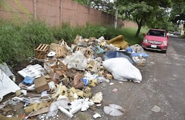 Montículo de basura en la calle, con colchones, cajas de madera y bolsas plásticas, sin personas visibles.