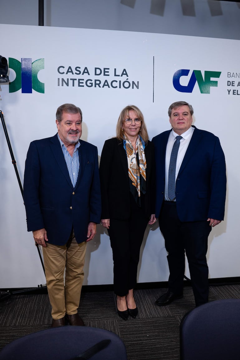 Liz Crámer en traje negro con pañuelo colorido, Alberto Acosta y Osfaldo Serafini con blazers azules, posando en un ambiente formal.