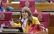 Celeste Amarilla con saco amarillo y blusa blanca, gesticulando mientras habla en el espacio legislativo rodeada de audiencia.