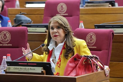 Celeste Amarilla con saco amarillo y blusa blanca, gesticulando mientras habla en el espacio legislativo rodeada de audiencia.