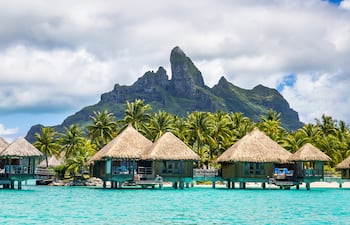 Un paisaje maravilloso de mar, montaña y bungalows en la Polinesia Francesa.