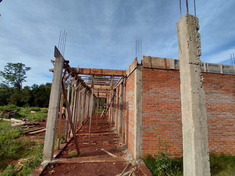 Obra en construcción de Colegio Nacional Catalina Salinas de Cáceres con pilares de concreto y paredes de ladrillo, rodeada de escombros.