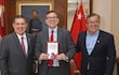 Horacio Cartes en traje gris oscuro sostiene su libro, mientras José Duarte Penayo y Oscar Nicanor Duarte Frutos sonríen en un despacho con banderas.