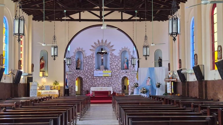 Interior de la Parroquia Virgen del Rosario, con altar decorado y estatuas de santos visibles en un ambiente iluminado.