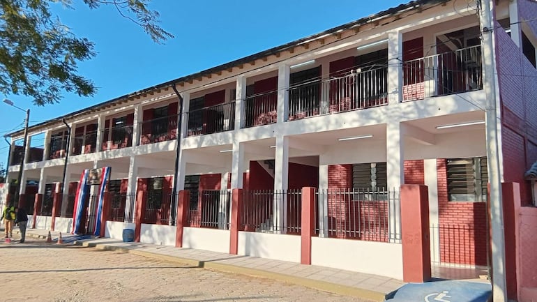 Edificio de dos pisos, paredes blancas y rojas, en entorno urbano luminoso y despejado.