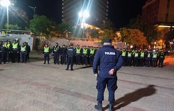 Grupo de agentes uniformados coordinando bajo luces urbanas, con un oficial gesticulando al frente.