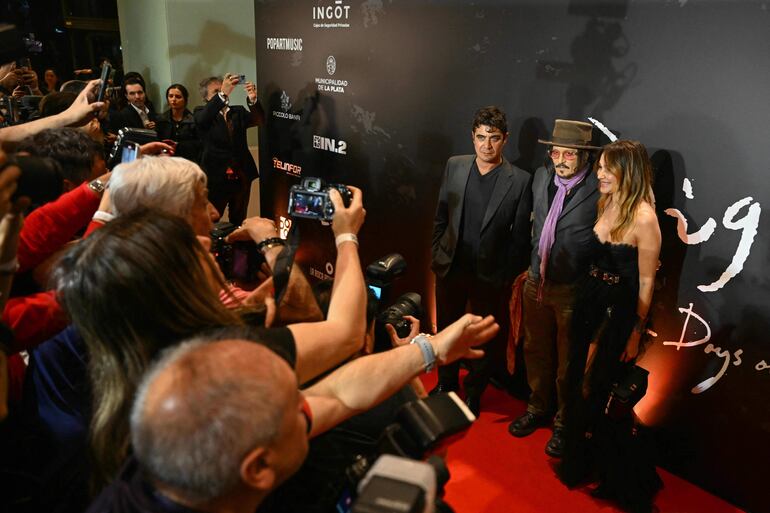 El actor y director estadounidense Johnny Depp posa para una foto con el actor italiano Riccardo Scamarcio y la presentadora de televisión argentina Verónica Lozano a su llegada a la alfombra roja para el preestreno de su nueva película "Modi, Three Days on the Wing of Madness". (Luis ROBAYO / AFP)