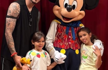 Antonio Sanabria, con tatuajes, posa en el centro rodeado de tres niñas sonrientes en un ambiente temático de Disney.