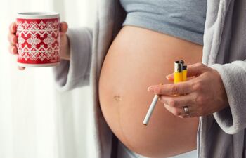 Mujer embarazada fumando y tomando café