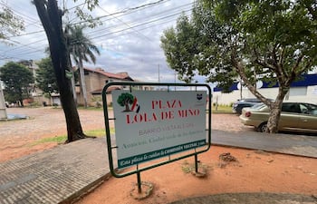 Cartel de la Plaza Lola de Miño en ambiente desértico, sin personas visibles, con vegetación y calles empedradas.