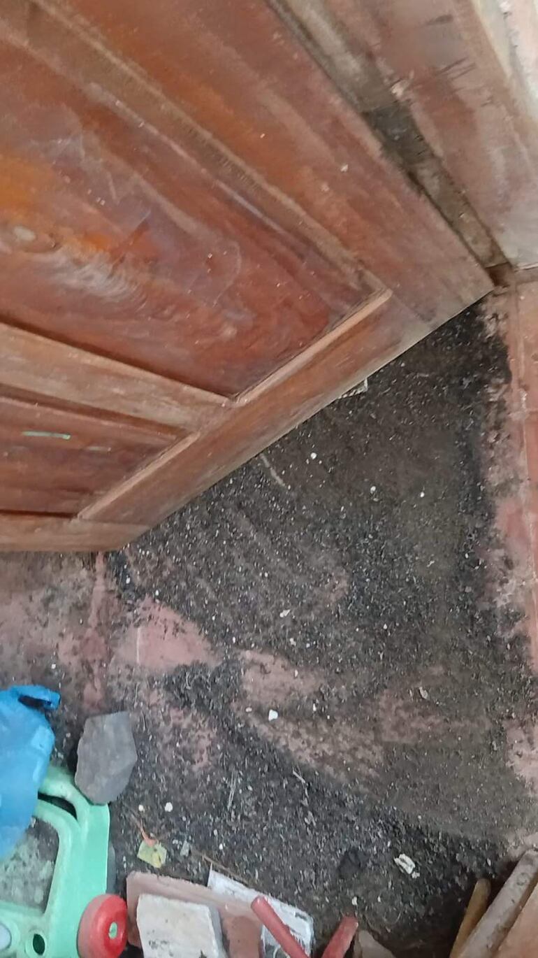 Entrada de la escuela La Residenta con suelo cubierto de tierra y un objeto de plástico verde con ruedas.