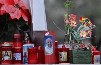 Una vela con una imagen del Papa Francisco se encuentra debajo de una estatua del Papa Juan Pablo II en el hospital Gemelli donde el Papa Francisco está hospitalizado para pruebas y tratamiento por bronquitis en Roma.