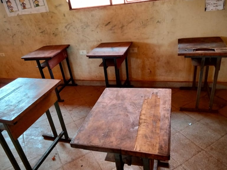 La imagen muestra algunas mesas reacondicionadas sin sillas que los alumnos utilizan en las clases