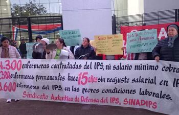 Marina Ayala y otras mujeres sostienen pancartas en protesta frente al IPS, transmitiendo mensajes sobre condiciones laborales.