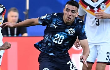 Braian Ojeda con camiseta negra y número 20 intenta controlar el balón, mientras un jugador alemán se acerca para defender.