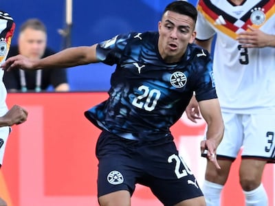 Braian Ojeda con camiseta negra y número 20 intenta controlar el balón, mientras un jugador alemán se acerca para defender.