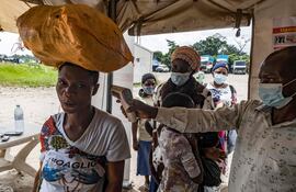 Un funcionario de sanidad fronteriza en el cruce de Busunga, entre Uganda y la República Democrática del Congo, toma la temperatura de un viajero con un termómetro infrarrojo sin contacto en Bundibugyo.