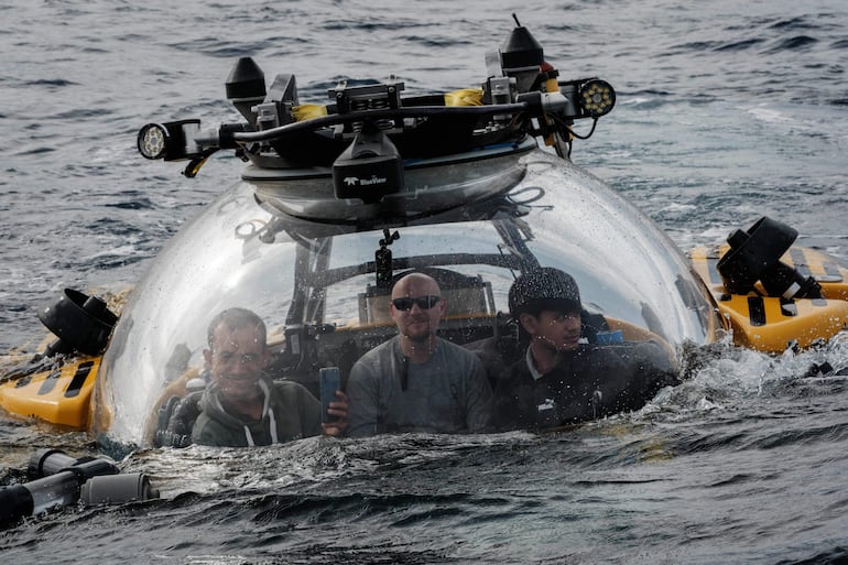 Esta foto, tomada el 12 de enero de 2026, muestra a un piloto (centro) y a científicos marinos indonesios sentados dentro de un sumergible tras ser liberados del OceanXplorer, un buque de investigación operado por la organización marina sin fines de lucro OceanX, para iniciar una inmersión en aguas frente a la isla de Célebes (Sulawesi).