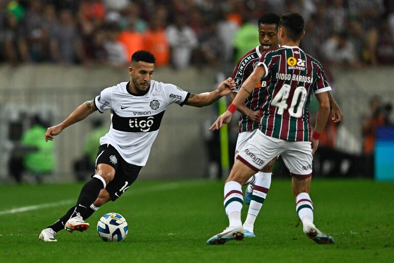 Fernando Cardozo (i), jugador de Olimpia, domina el balón frente a dos jugadores de Fluminense en el partido de ida de los cuartos de final de la Copa Libertadores 2023 en el estadio Maracaná, en Río de Janeiro, Brasil.