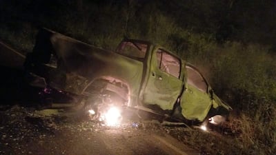 Camioneta volcada y quemada en un entorno rural, con vegetación alrededor y sin personas visibles.