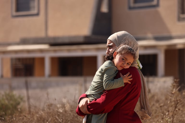 Una mujer y su hija observan a los colonos israelíes que asedian sus casas.