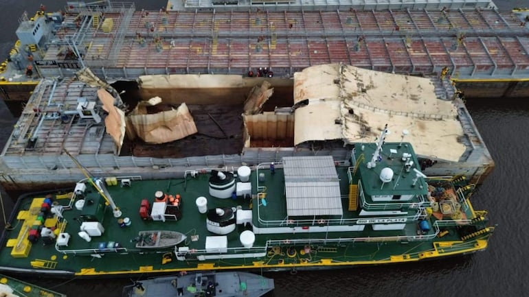 Vista aérea de una barcaza con daños significativos tras explosión, con otra embarcación de apoyo cerca.