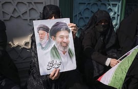 Un mujer porta una pancarta con la imagen del nuevo líder supremo de Irán, Mojtaba Jameneí, y su padre y antecesor en el cargo, Alí Jameneí.
