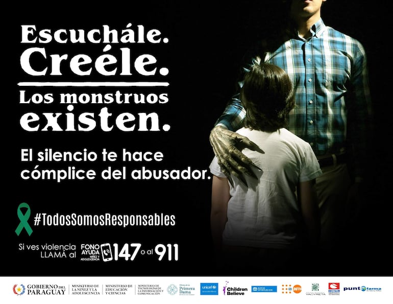 Adulto con camisa a cuadros coloca su mano sobre el hombro de un niño con camiseta blanca, en un ambiente oscuro y tenso.