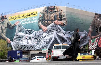 Una mujer pasa junto a una valla con el mensaje "El estrecho de Ormuz permanecerá cerrado" en la plaza Enghelb de Teherán.