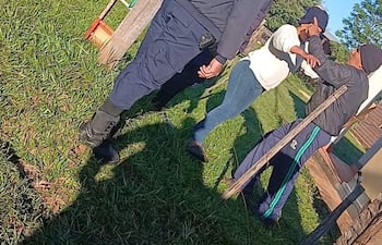 Tres hombres con uniformes policiales conversan con un hombre en suéter claro y pantalones ajustados, en un entorno de césped.
